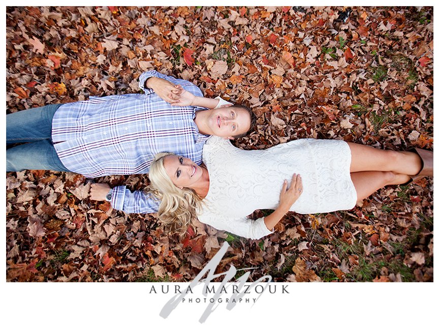 Couple lies in the fall leaves at their Pisgah National Forest engagement session. © Aura Marzouk Photography, Greensboro Wedding Photographer