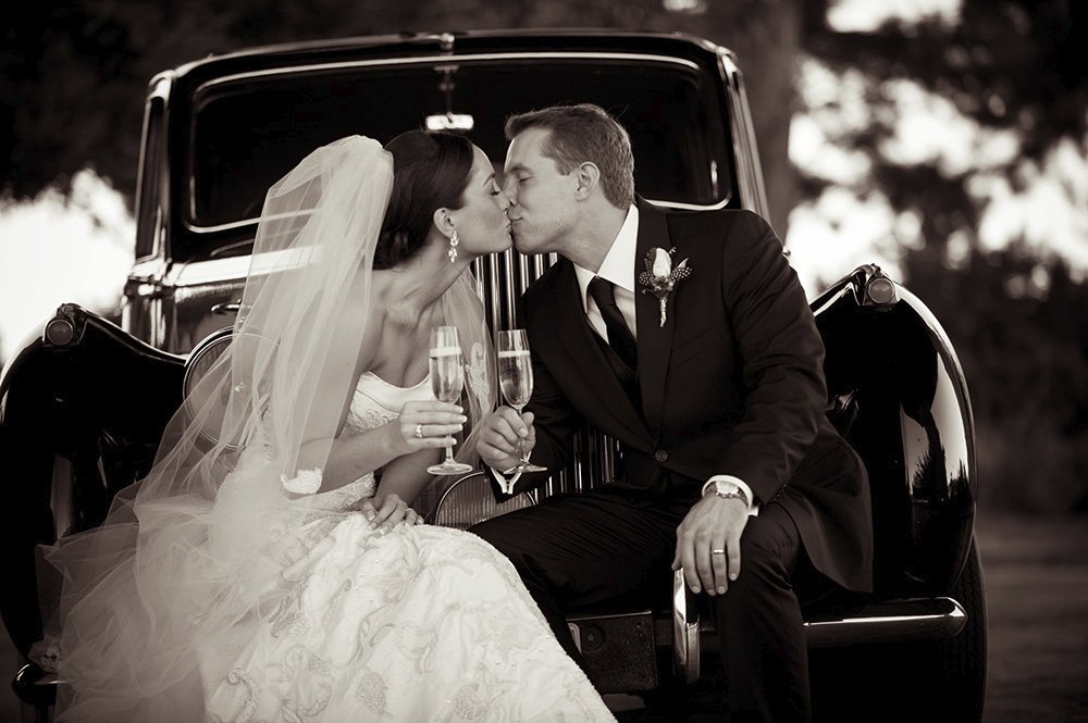 Just married couple enjoying kiss & champagne on Rolls Royce