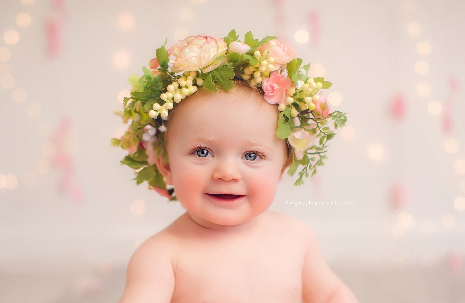 smiling baby girl with blue eyes, wearing flower crown