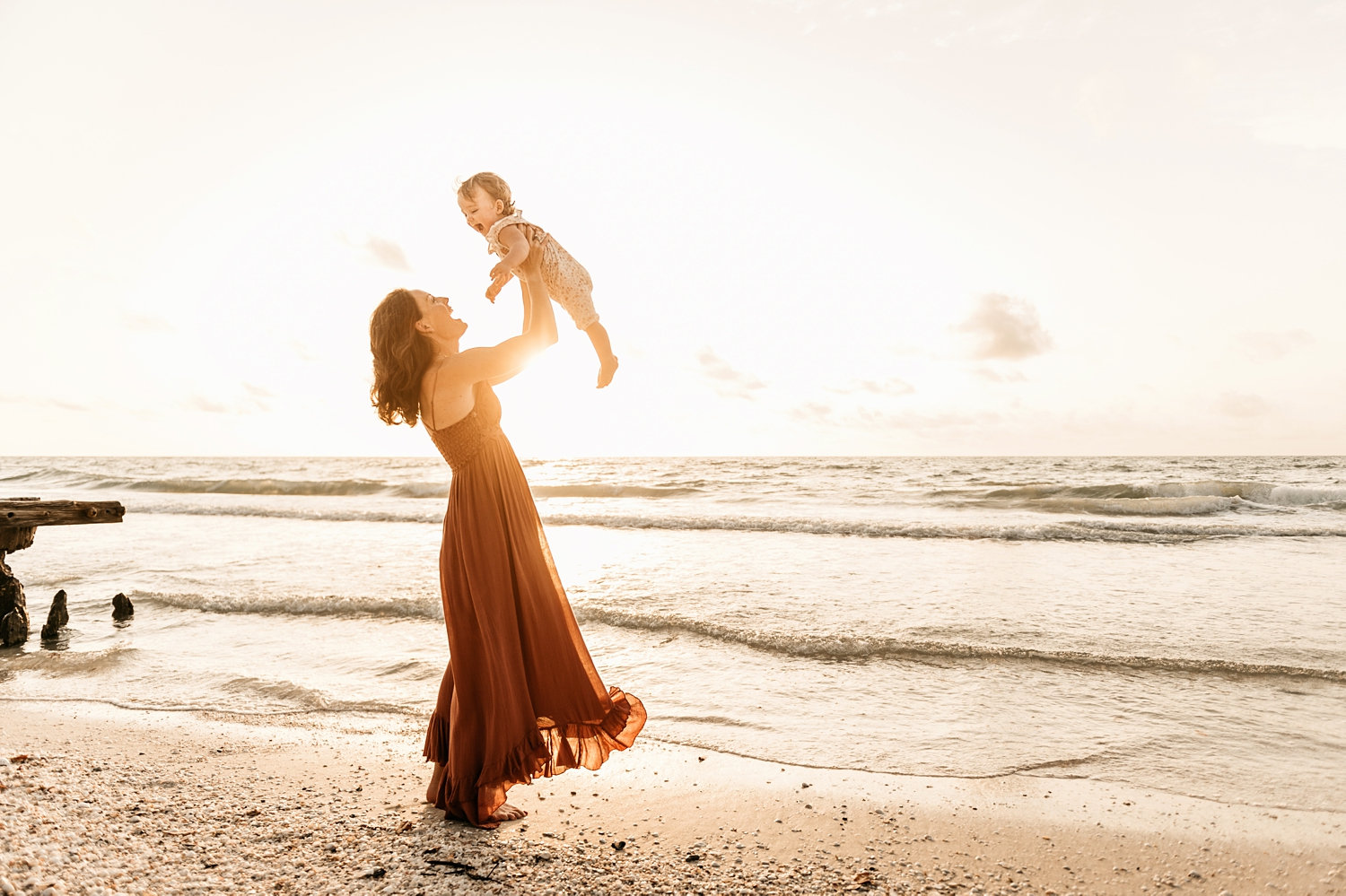 mom holding up smiling baby girl at the beach, Naples Beach, Florida, Rya Duncklee