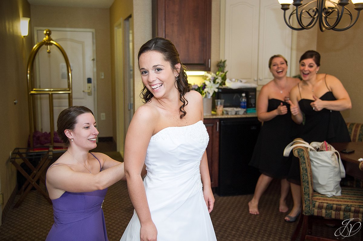 bride getting dressed with bridesmaids being silly