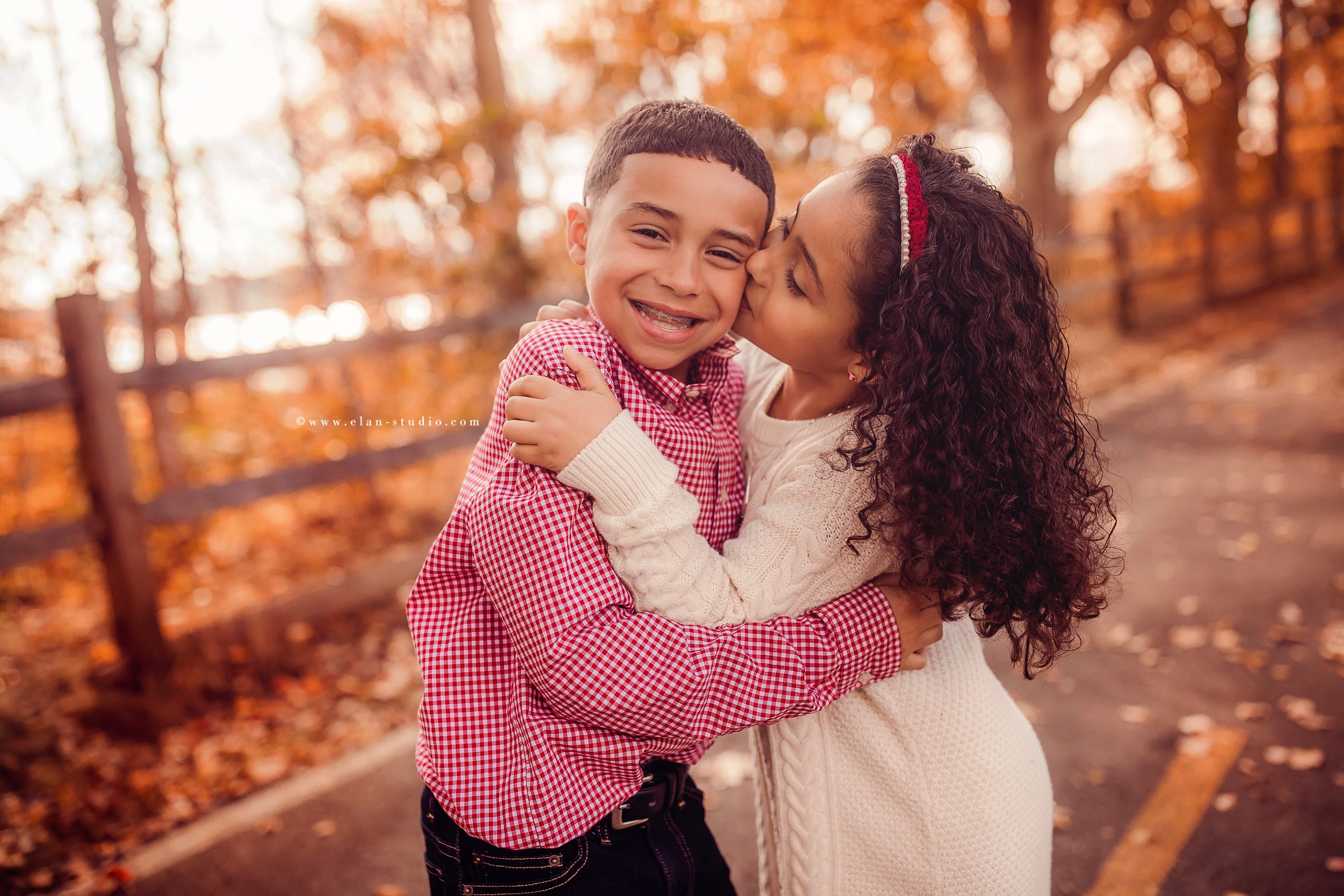 girl kissing brother on the cheek, gingham shirt, ivory sweater dress, curly hair, braces, fall
