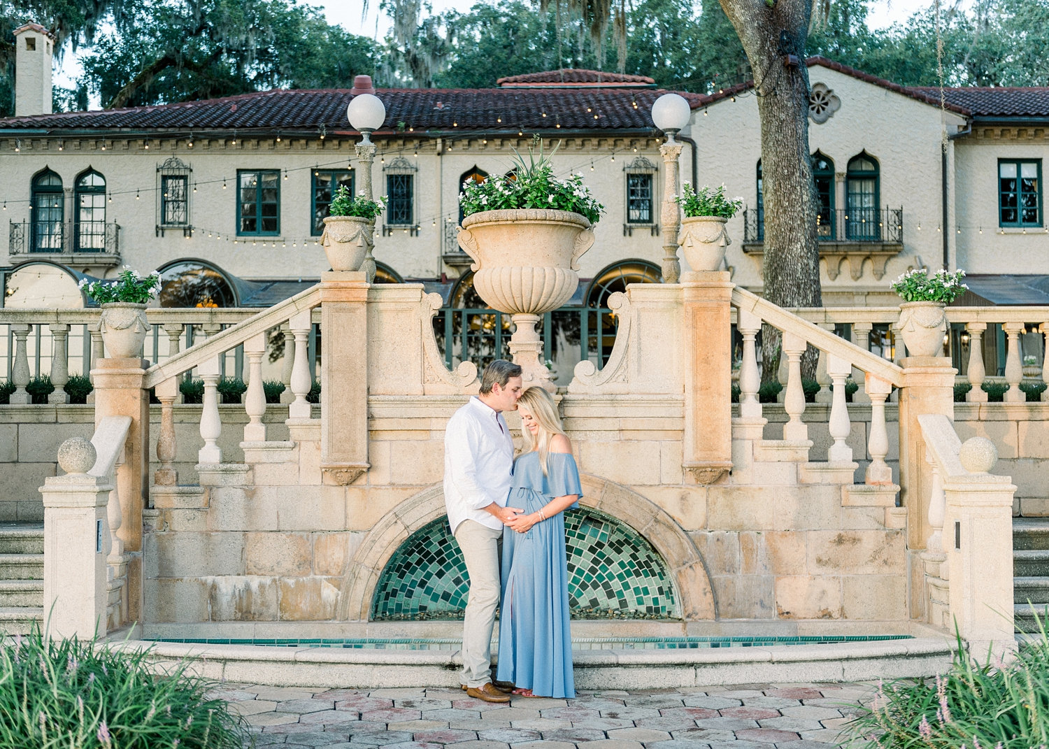 happy parents to be standing at the base of a fountain on the grounds of a Spanish estate in Jacksonville, FL