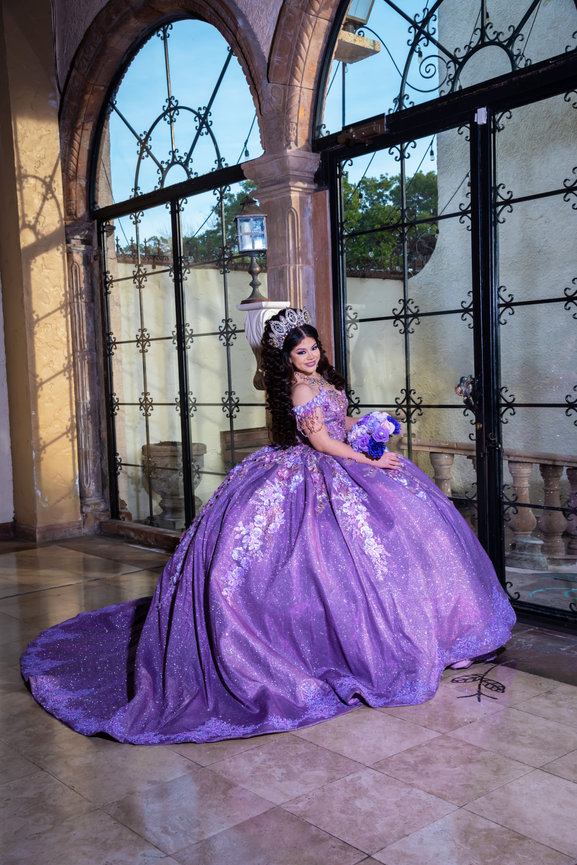 Quinceañera in purple gown by windows
