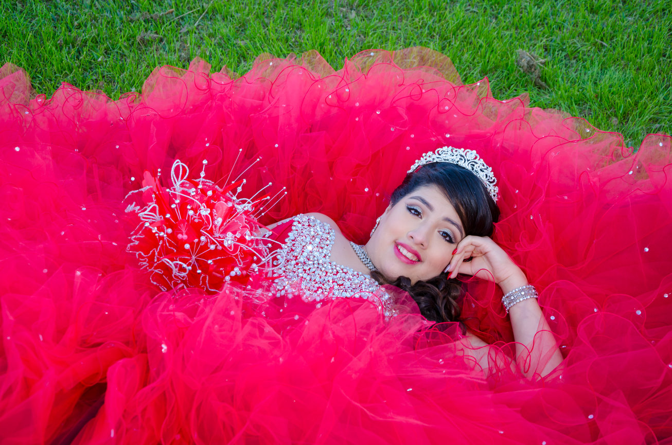 Young woman lying on grass in red gown