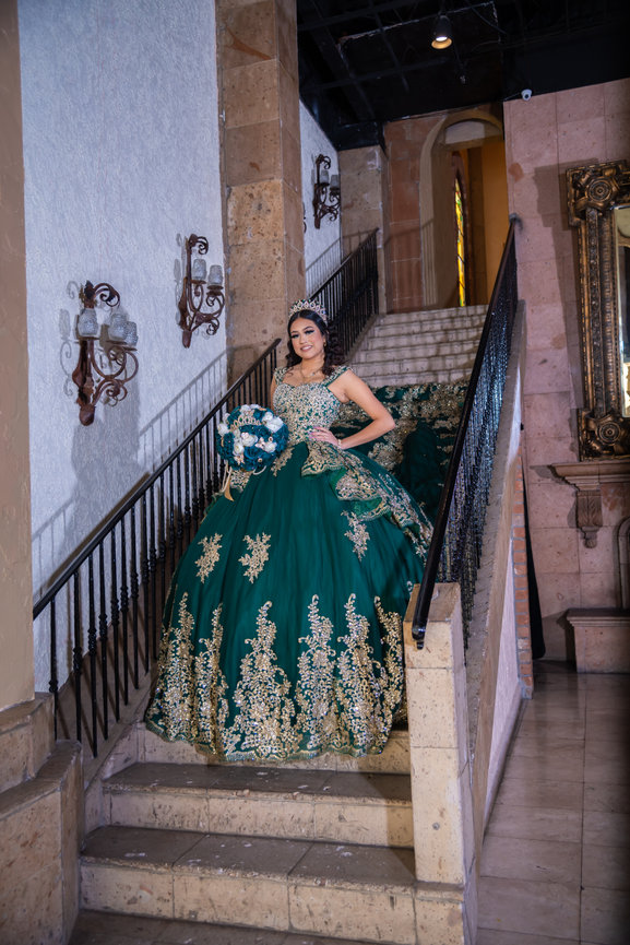Young woman in green gown descending staircase