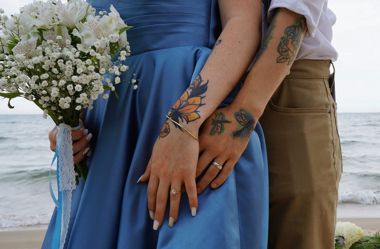 Couple standing together by the beach with a bouquet