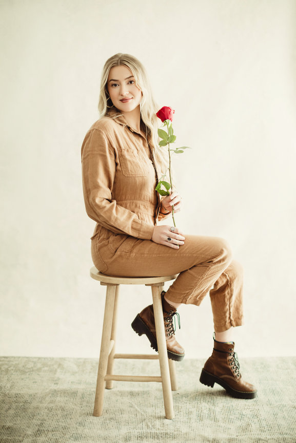 Natural light studio portraits of college graduate in khaki and tan styled romper with red rose, taken in a photo studio with Adam Trujillo, a Las Vegas portrait photographer.