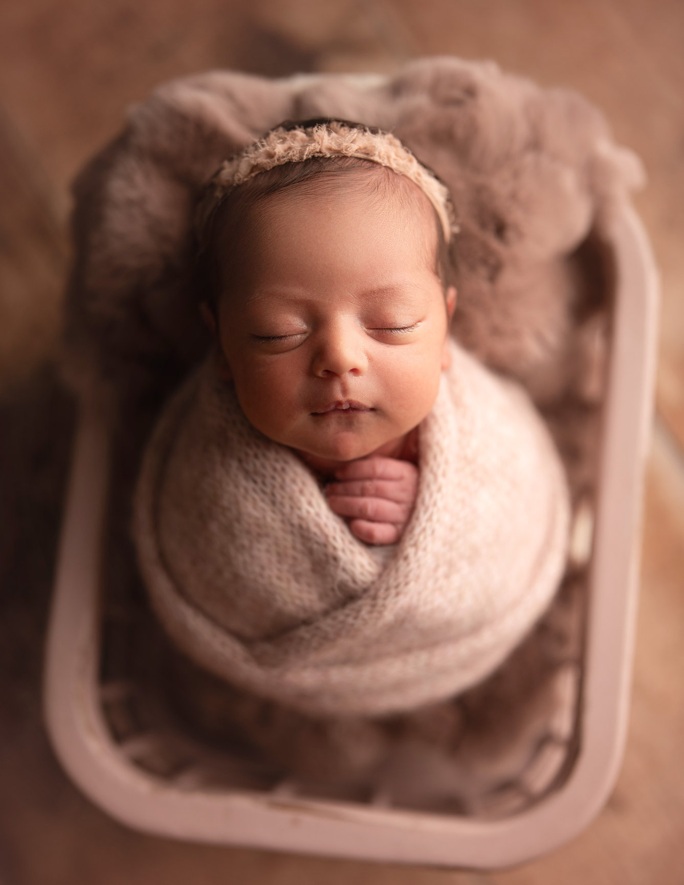 Newborn baby wrapped in a cream basket