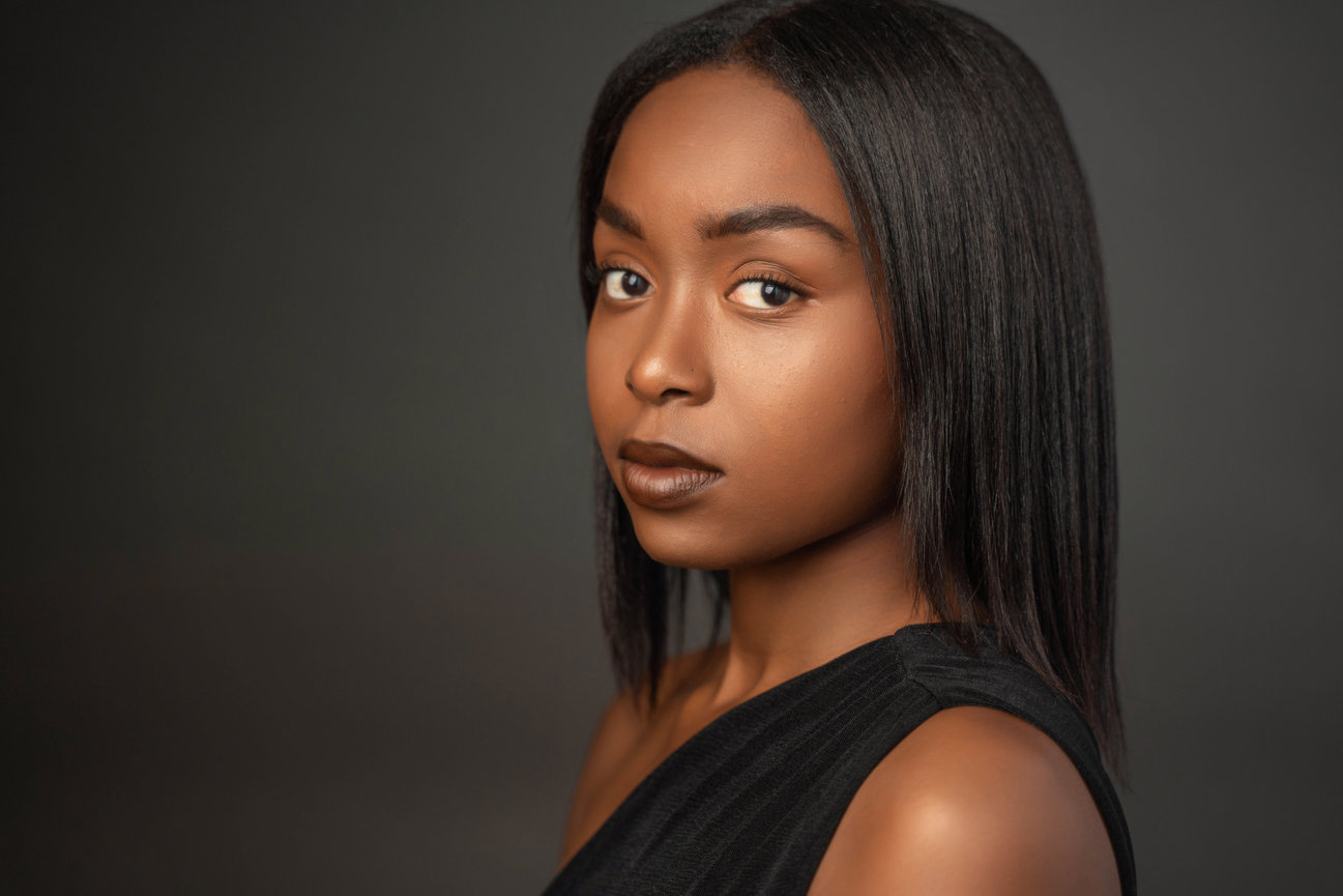 Woman in black top with a confident gaze and soft lighting.