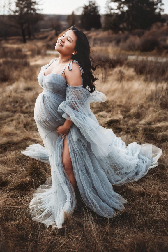 A beautiful pregnant woman in a blue gown standing in a field captured by a New Jersey maternity photographer.