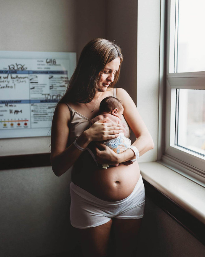 A new mother holds her newborn by the window of her hospital room during a Fresh 48 session at Morristown Medical Center.