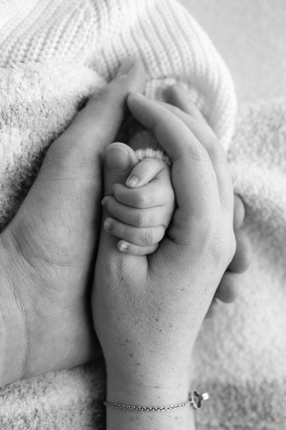 Newborn hand embraced by mother's hand and father's hand