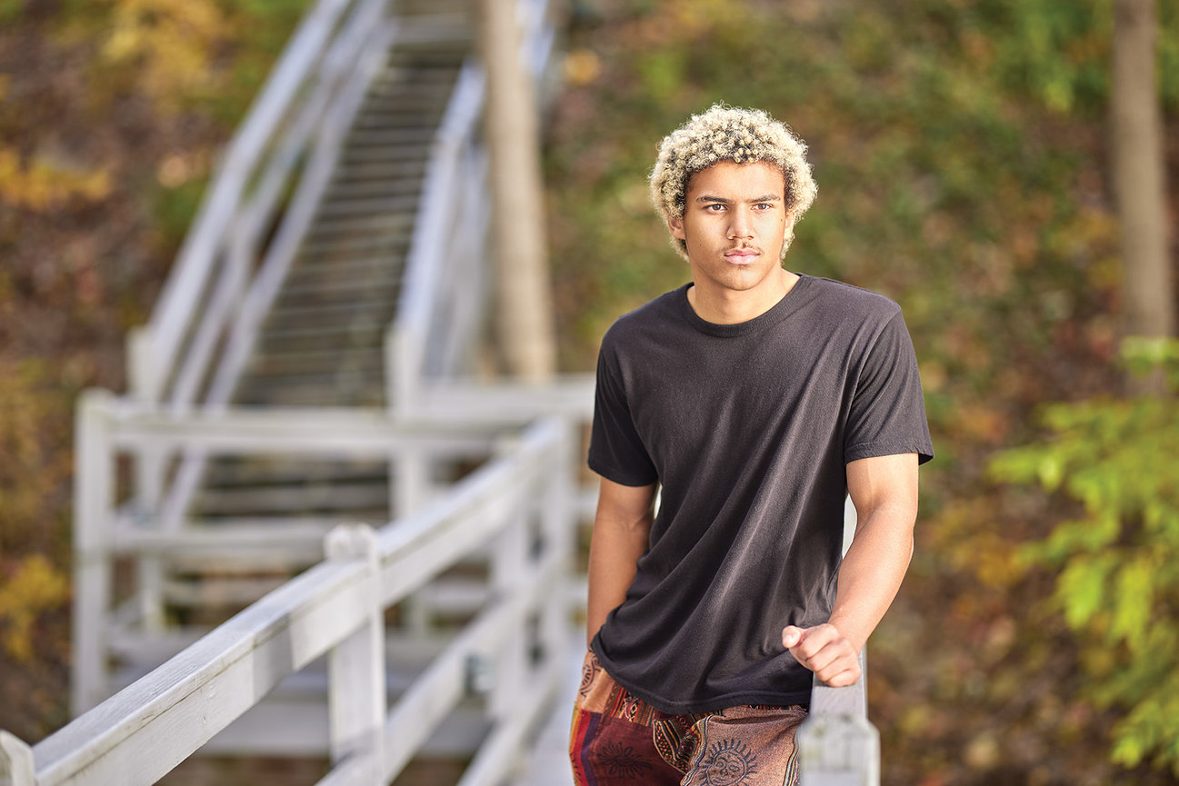 High school senior portrait of a young man outdoors, photographed in natural light with a serious and confident expression