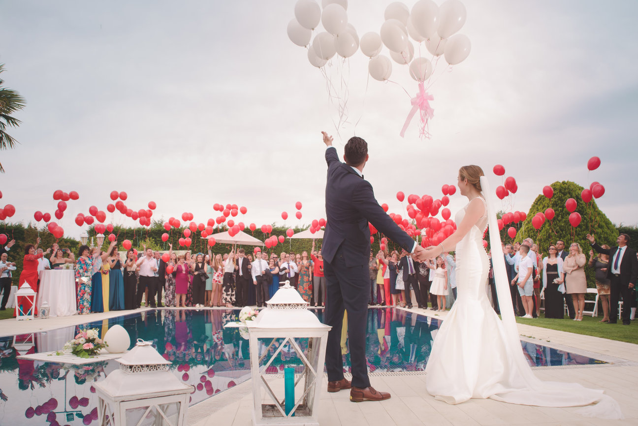 Bride and groom celebrate outdoors during a wedding ceremony with guests in the background.
