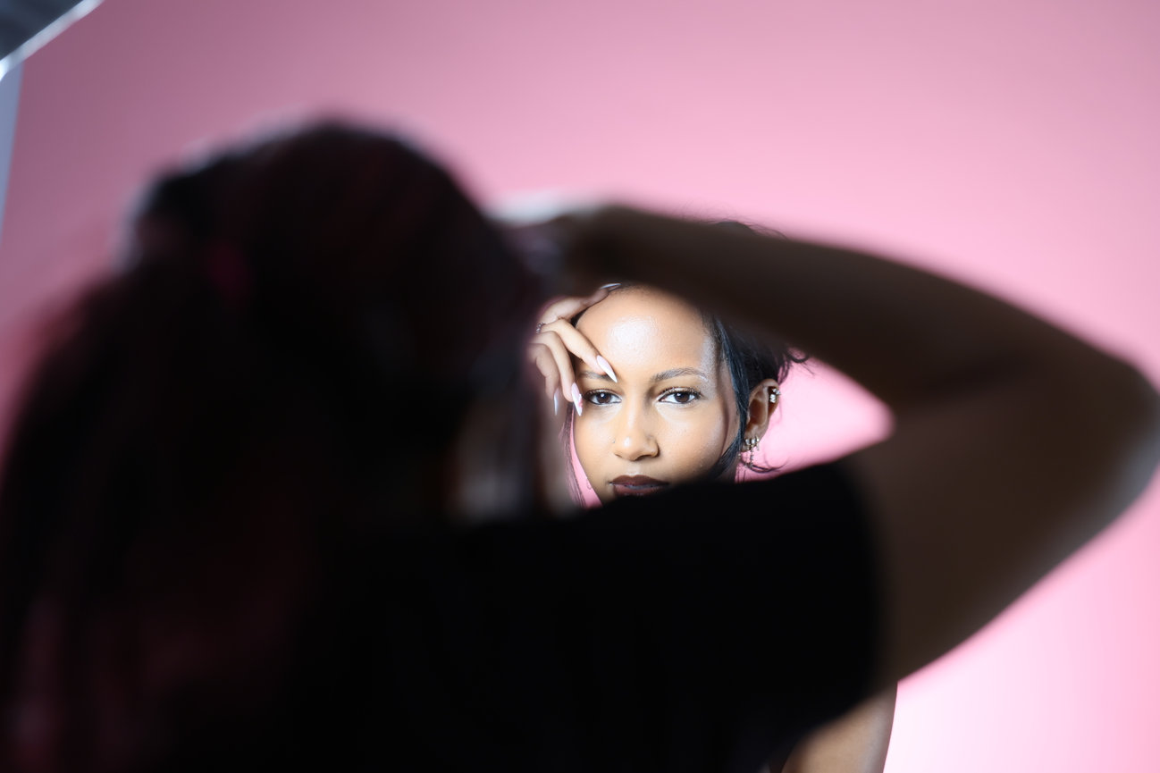 Photographer framing a woman against a pink background.