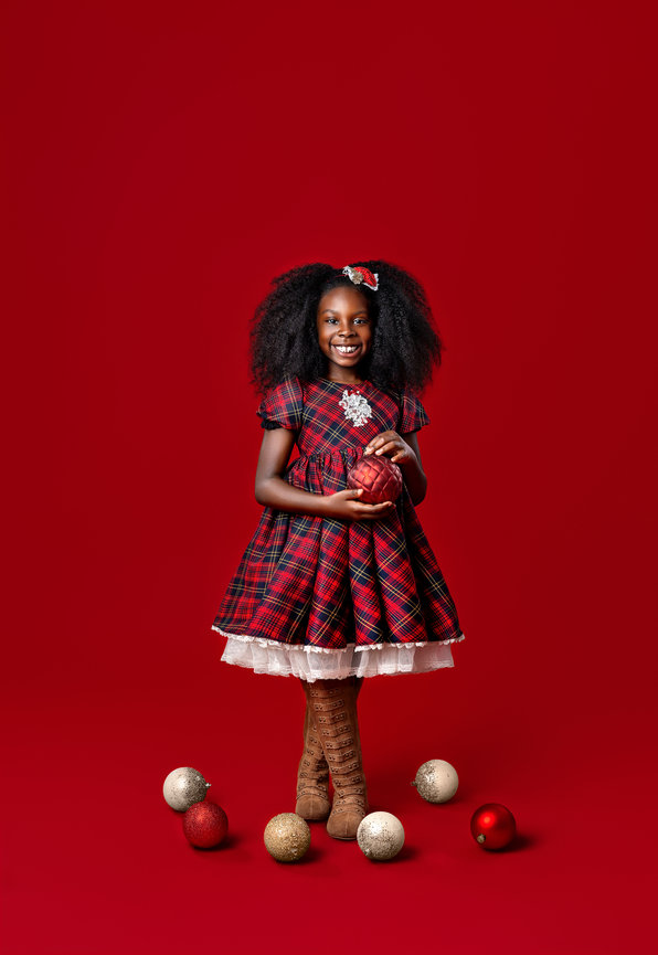 Fine art Christmas portrait of a child against an elegant red holiday studio backdrop in Northeast Ohio.
