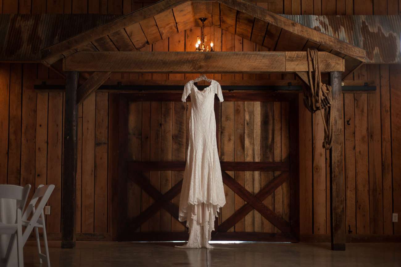 Lace wedding dress hanging from doorway at wedding venue.