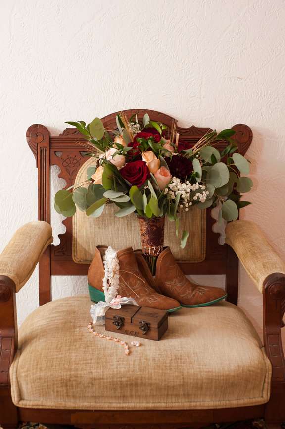 Bride's bouquet, wedding shoes and jewelry on a chair.