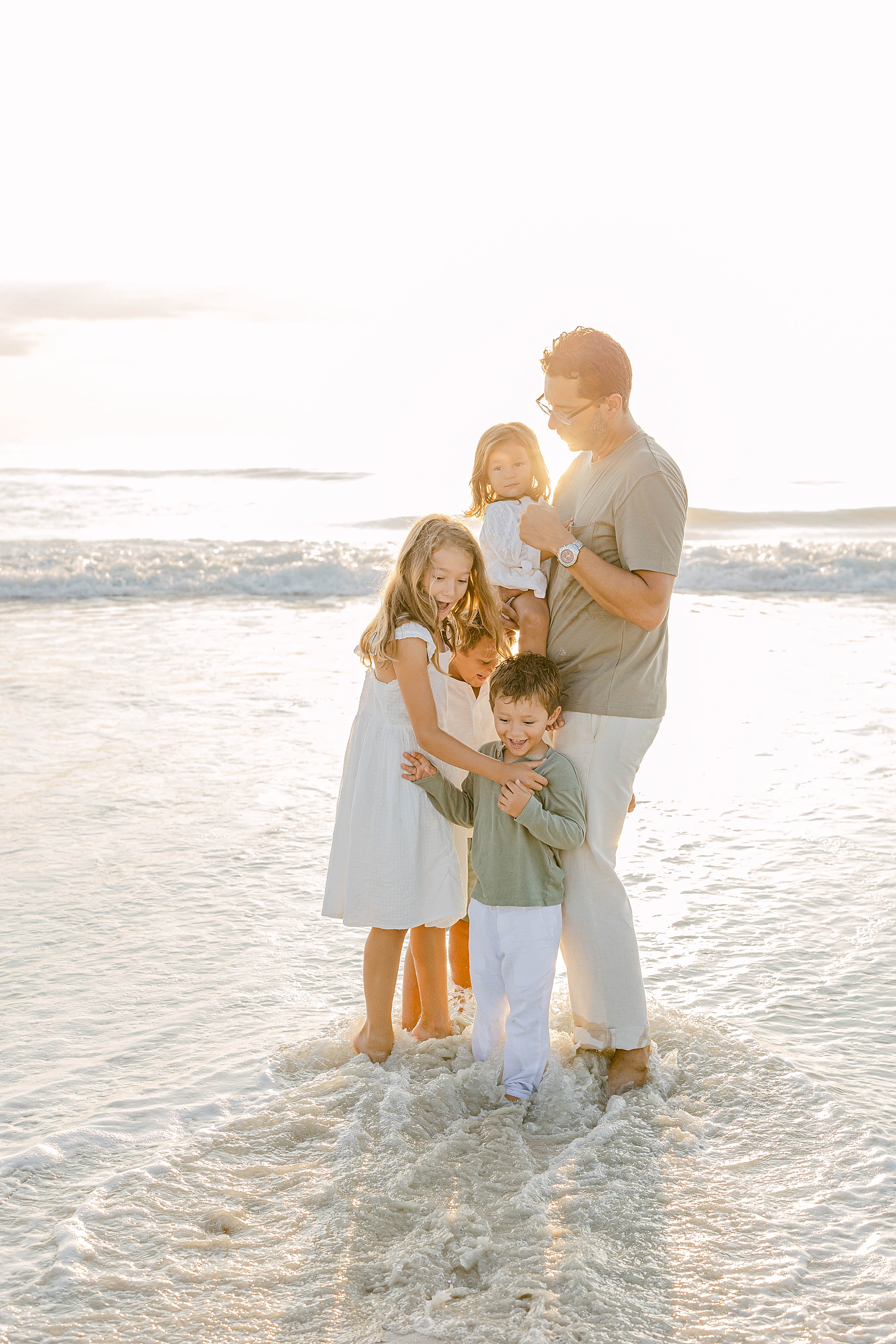 kids on beach at sunrise with their dad in the water