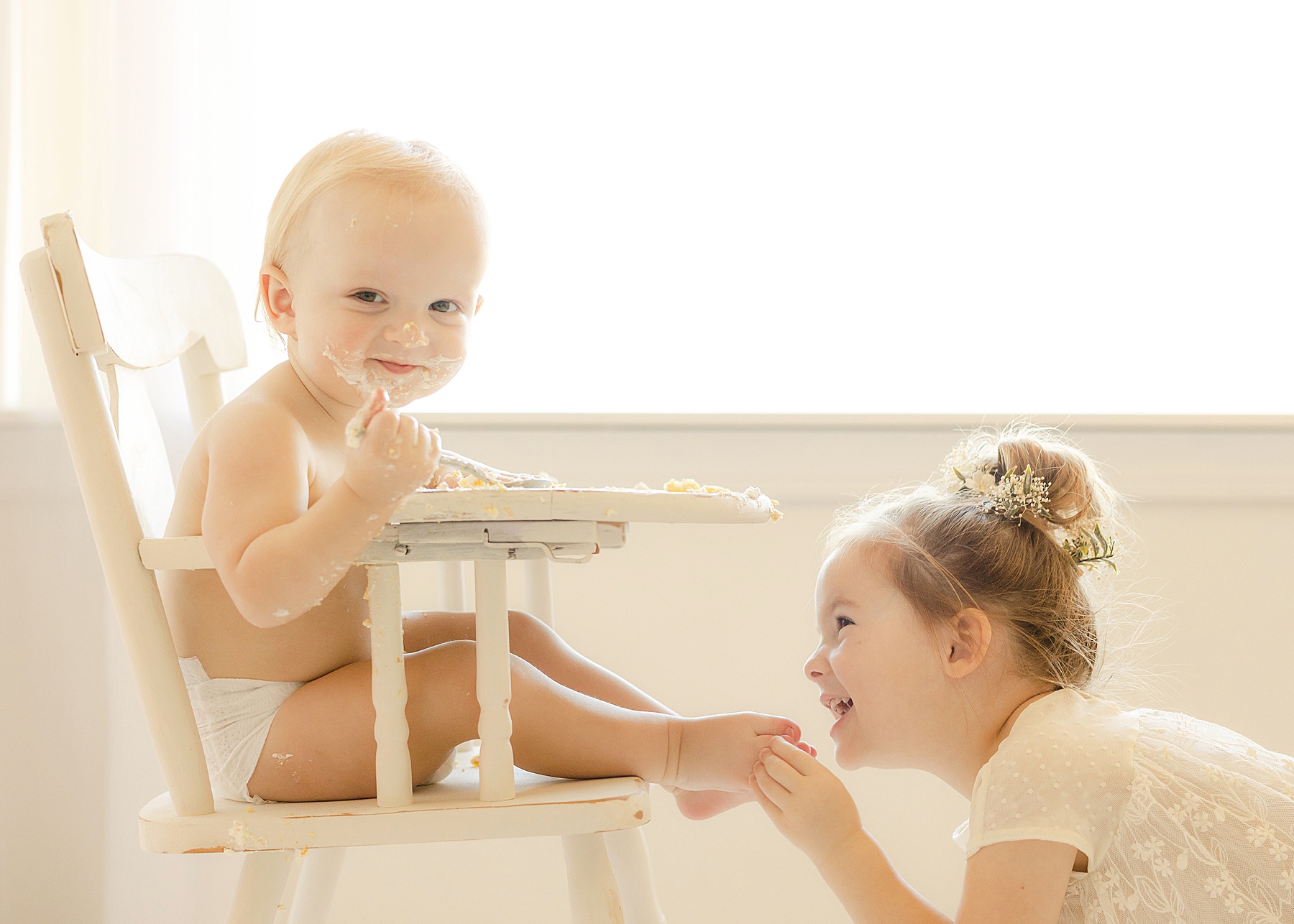 baby boy and little girl enjoying cake on a white background with minimal color