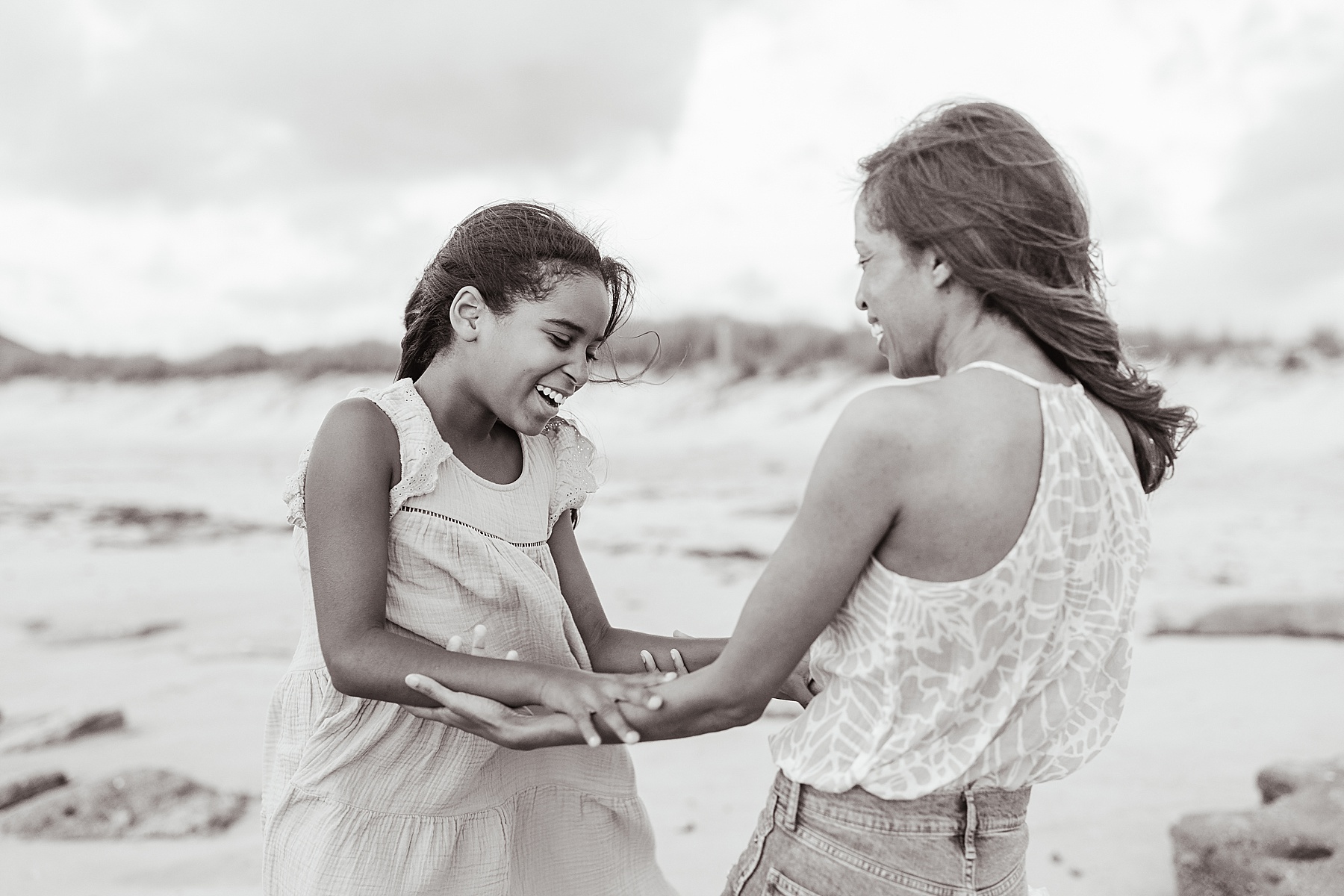 mother and daughter holding each others hands on the beach