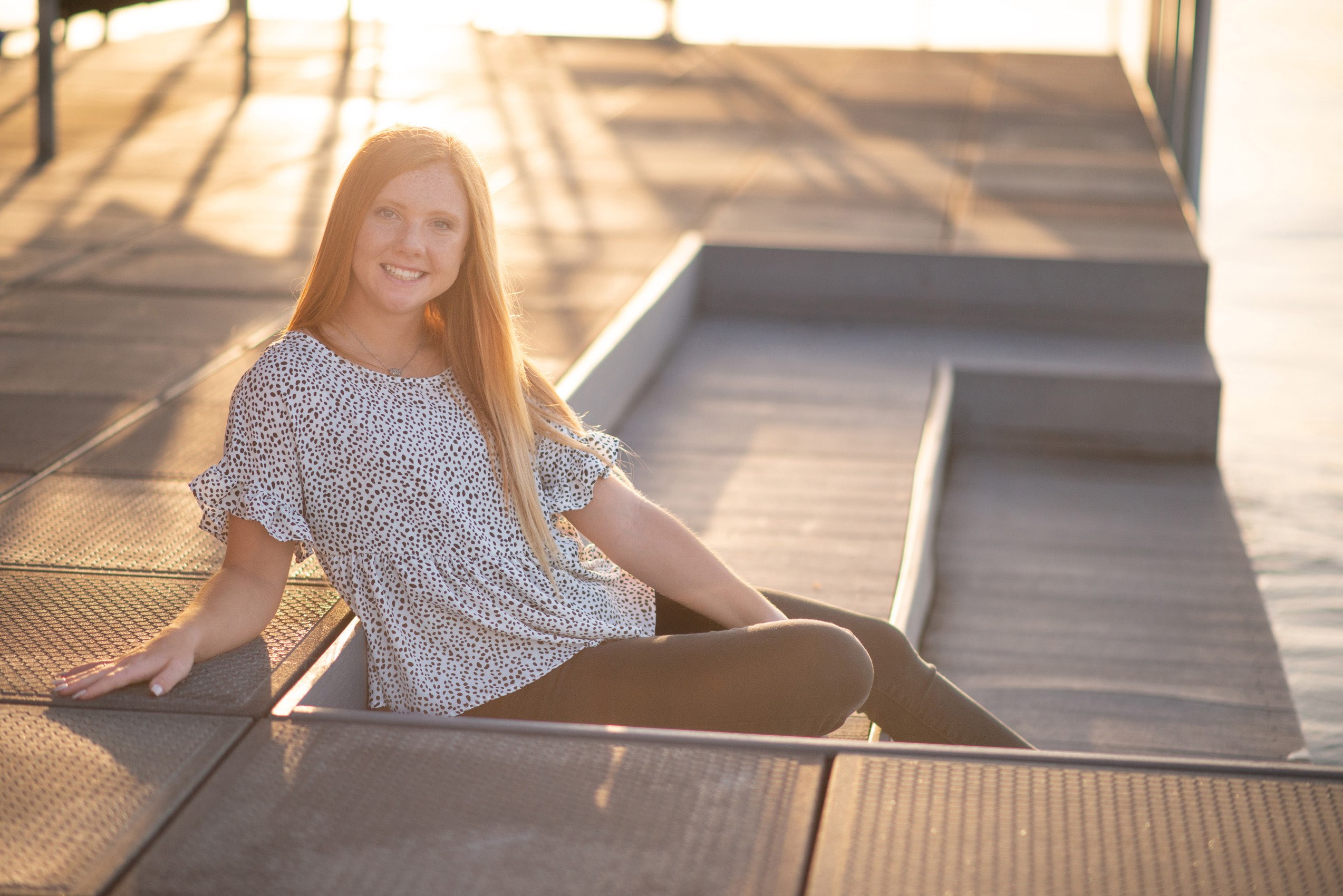 Senior girl in print top sitting on dock at Tablerock Lake.