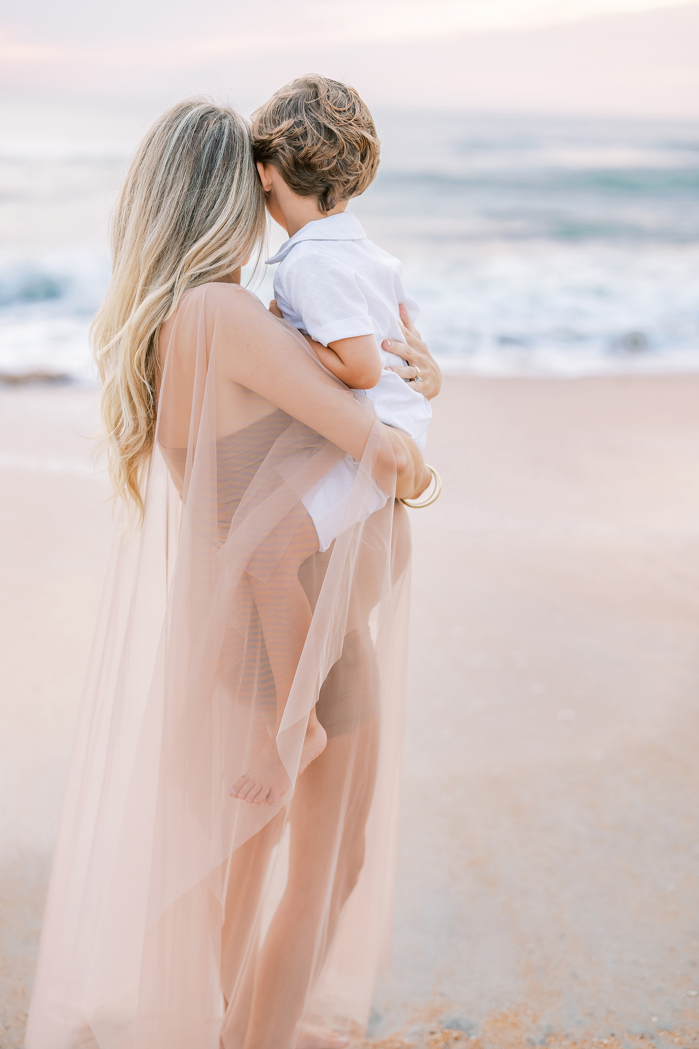 fine art light and airy portrait of pregnant woman with little boy at sunrise in Saint Augustine