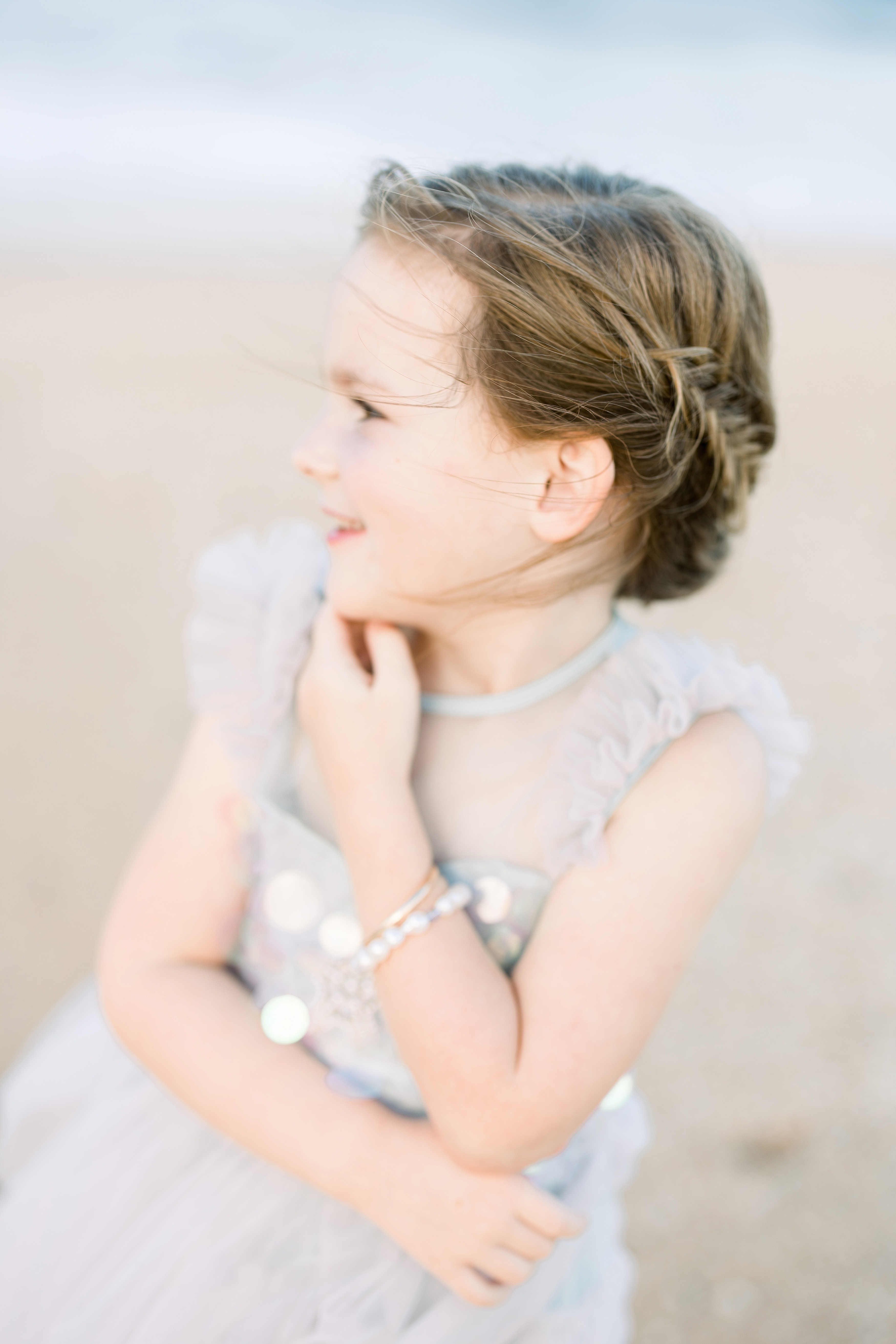 girl with mermaid braid and pearls in a pastel tulle dress playing on Saint Augustine Beach