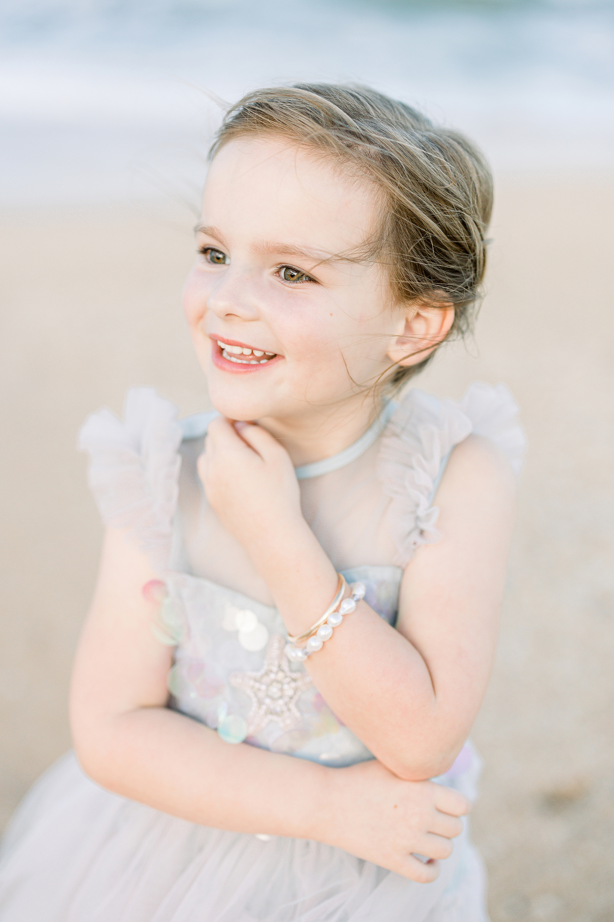 little girl in tutu du monde dress and pearls on the beach at sunset