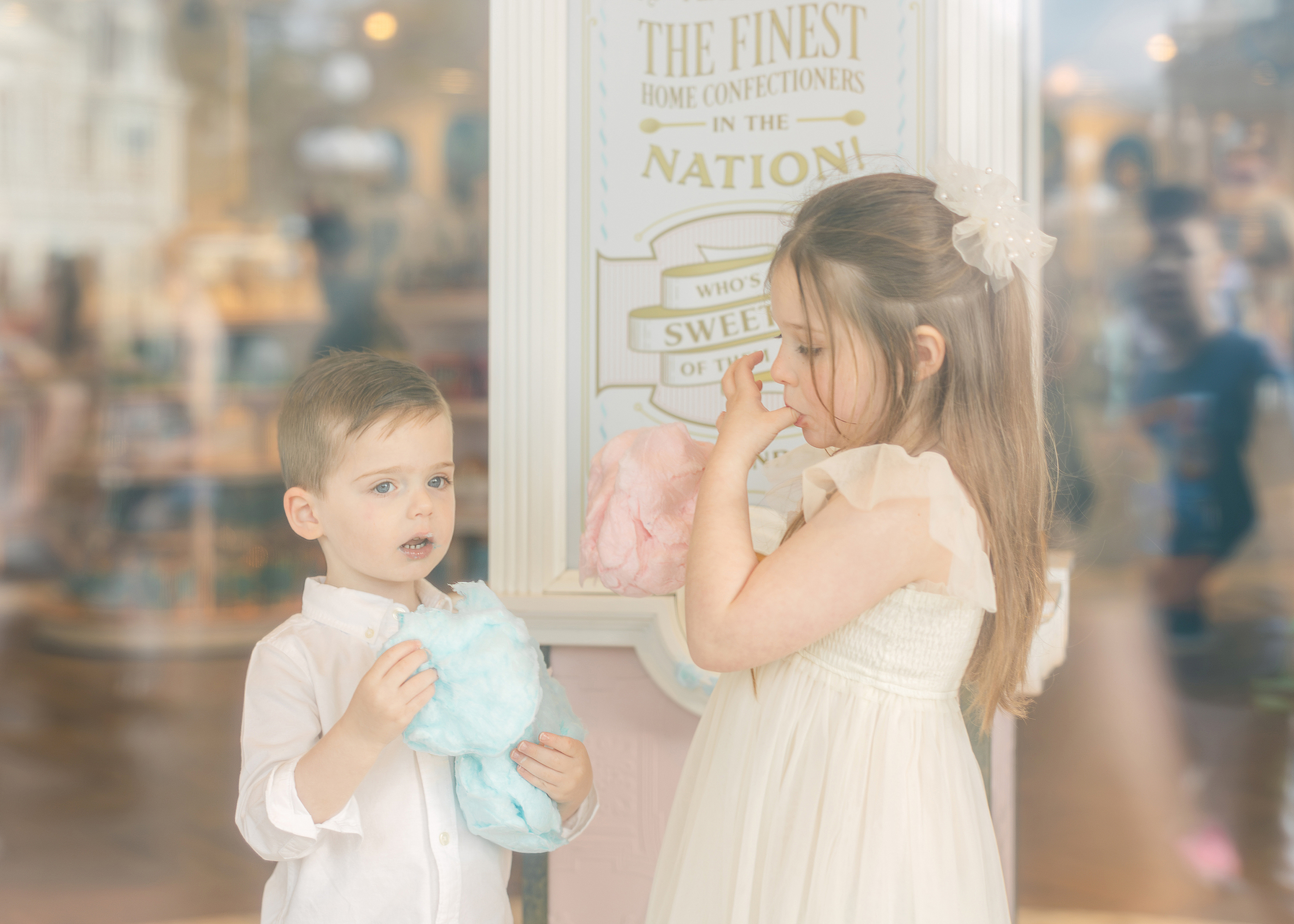 Two little children eat cotton candy together inside Main Street U.S.A confection shop at Magic Kingdom Park.