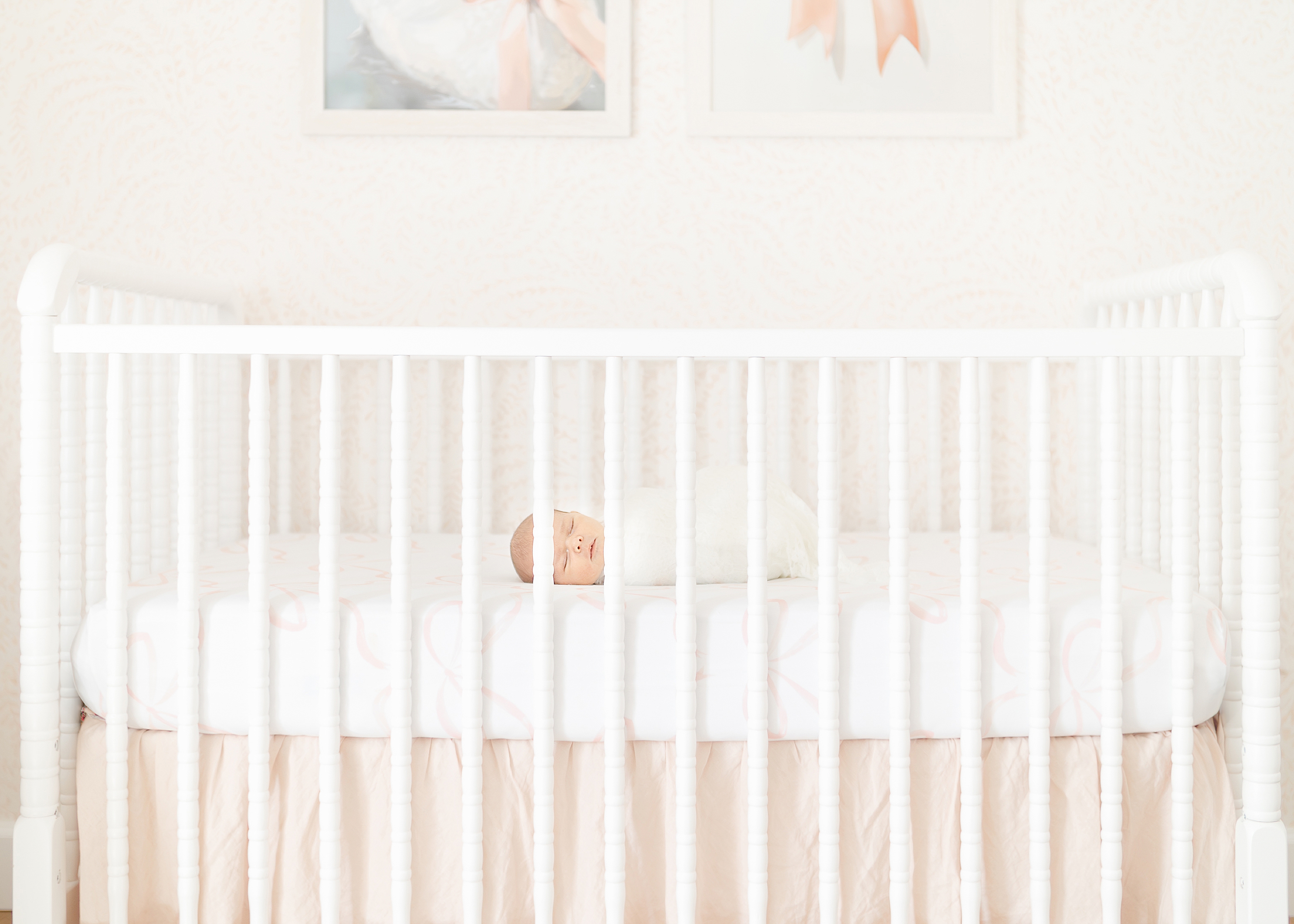 In home newborn portrait session of a pink and white nursery.