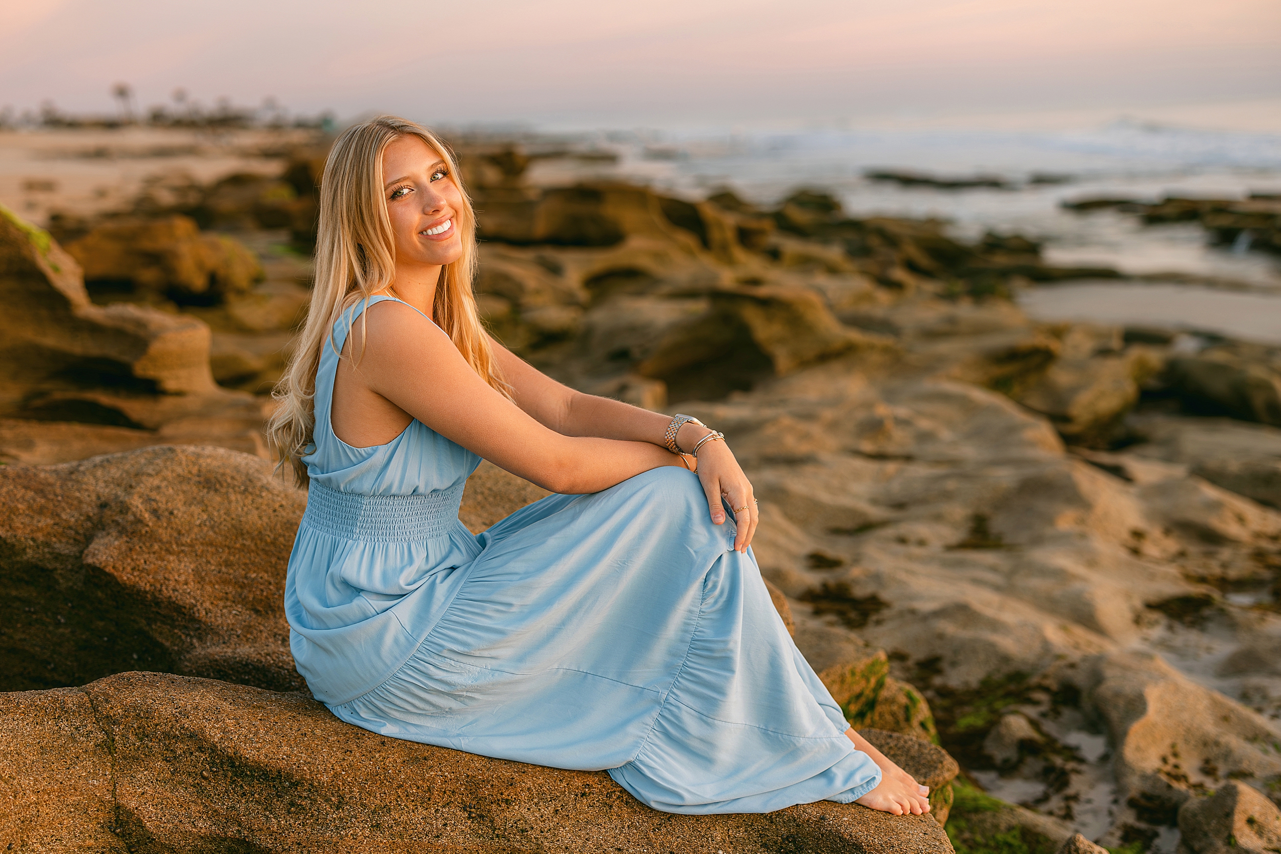 A young woman sits on the rocks at the beach in St. Augustine, Florida.