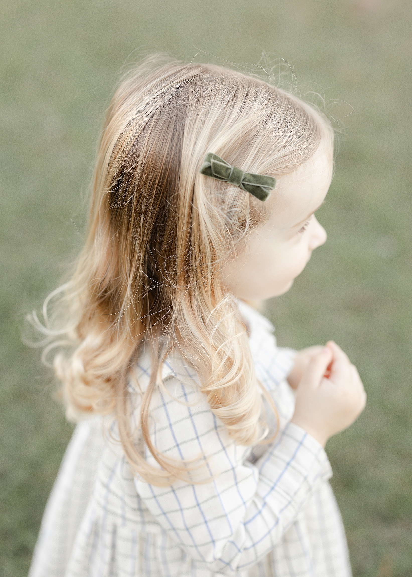 A fall portrait of a little girl's blonde curls with a green velvet bow.