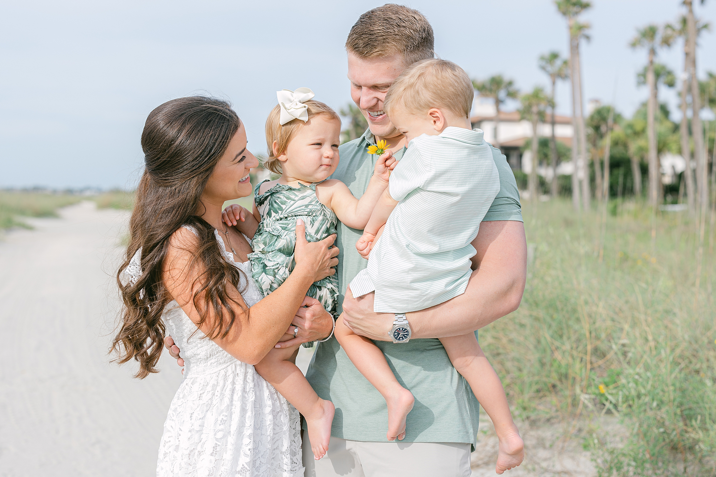 A family of four laughs together on the beach at Sea Island Resorts.