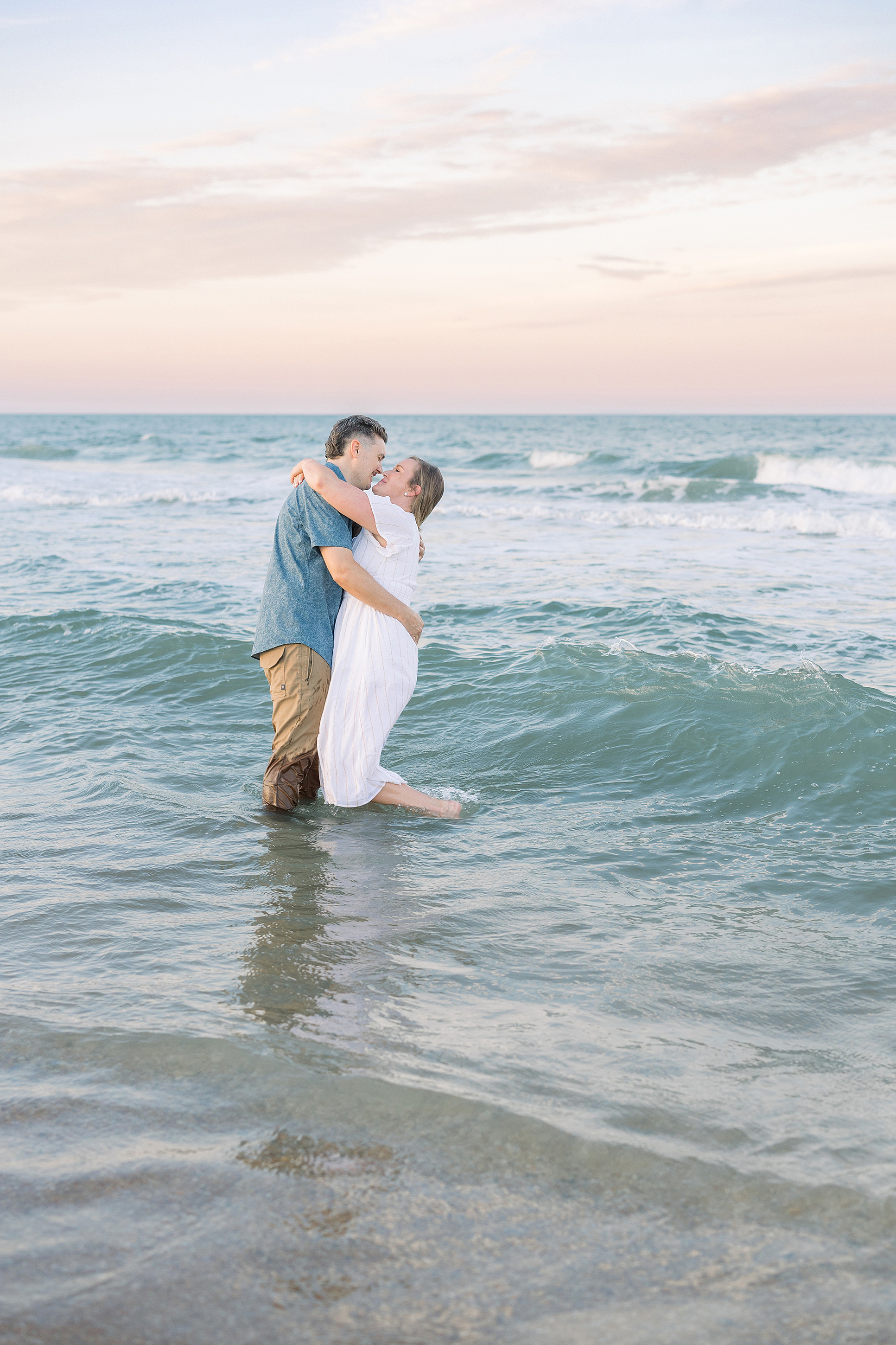 A colorful pastel portrait of a man and woman on the beach in the water at sunset.