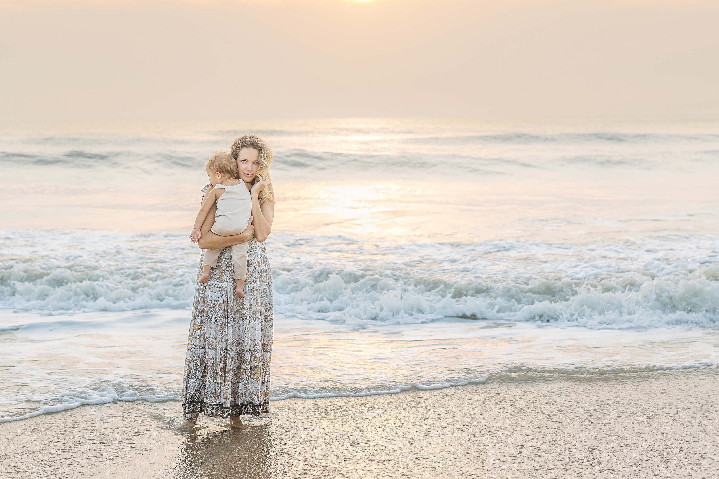 A light filled sunrise beach portrait of a woman staring at the camera on the beach at sunrise.