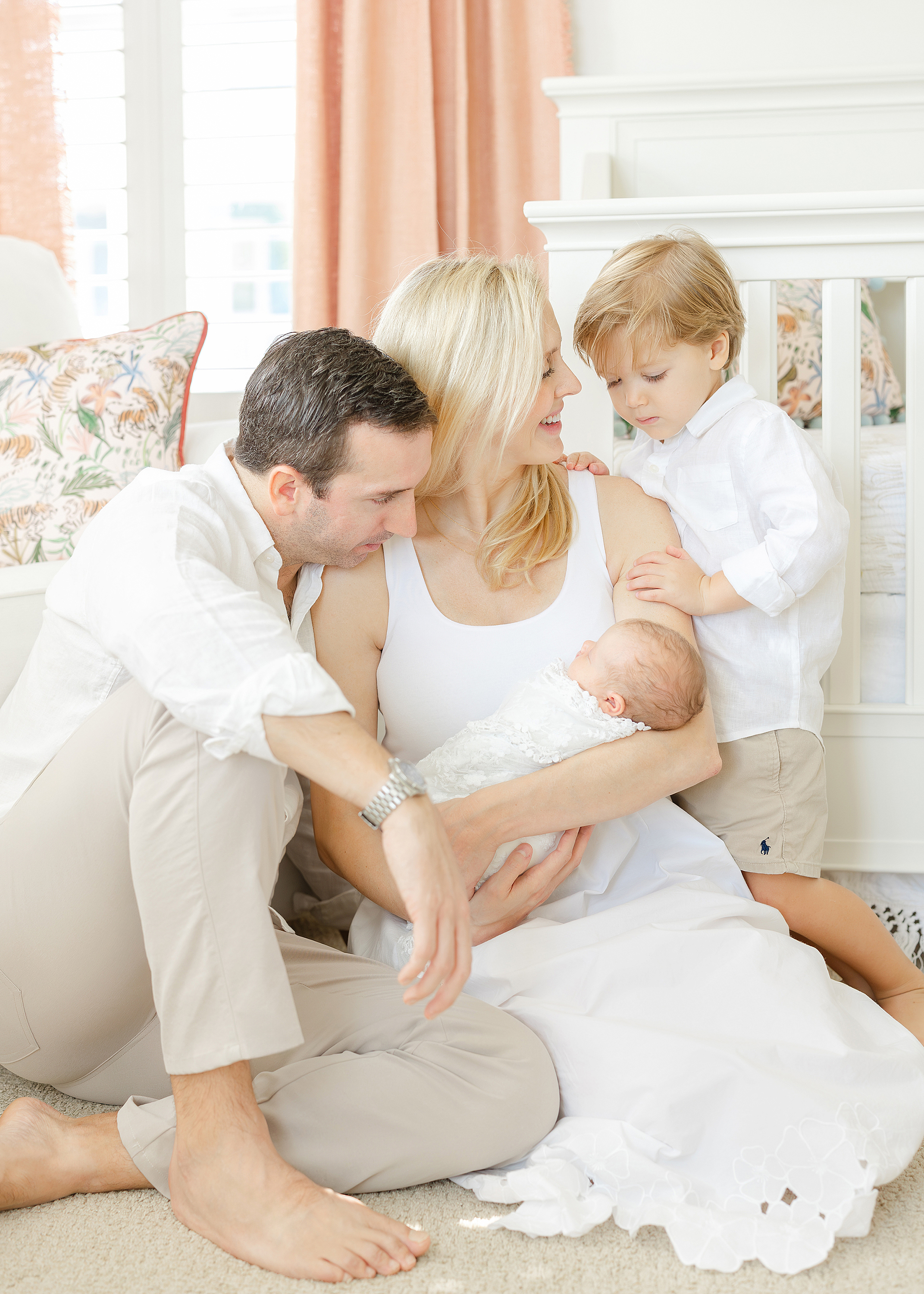 A family sits on the floor of their new baby girl's pink and white nursery in Ponte Vedra Beach, Florida.