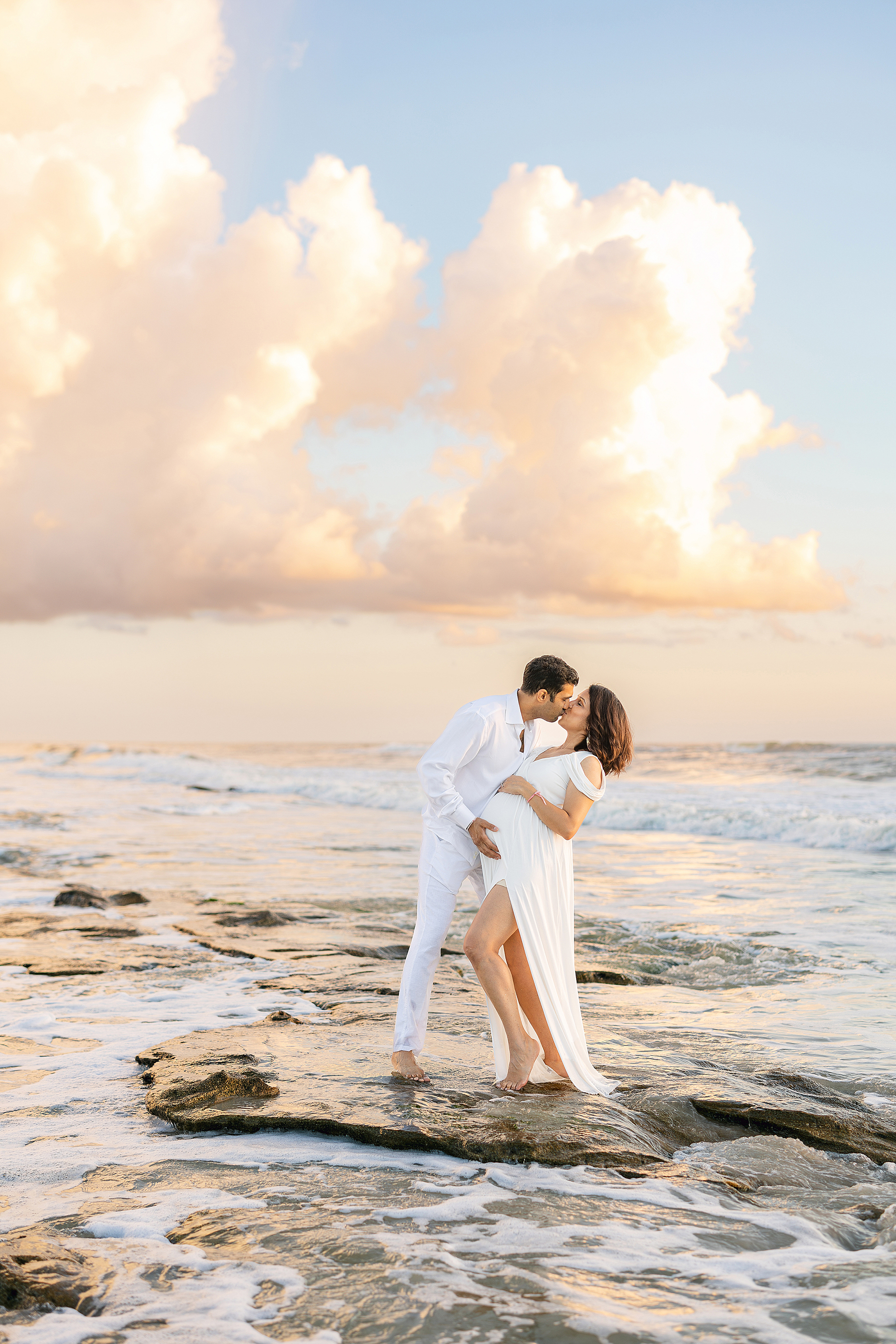 A man and a woman embrace on the rocks of Marineland in Saint Augustine Beach at sunrise.