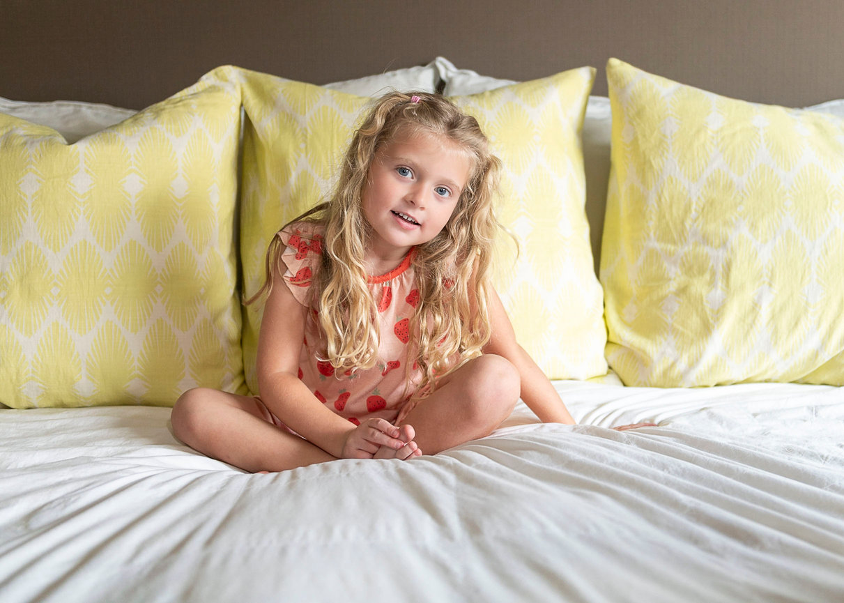 A young girl sitting criss cross on her parents bed.