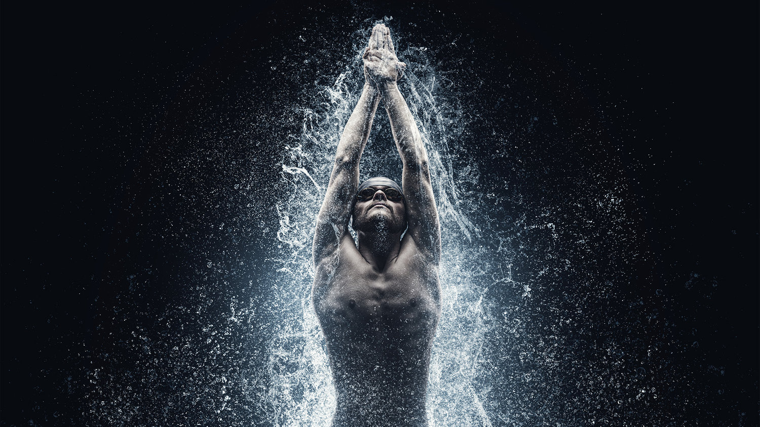 Swimmer emerging from water with arms raised, water splashing around, captured in dramatic lighting.