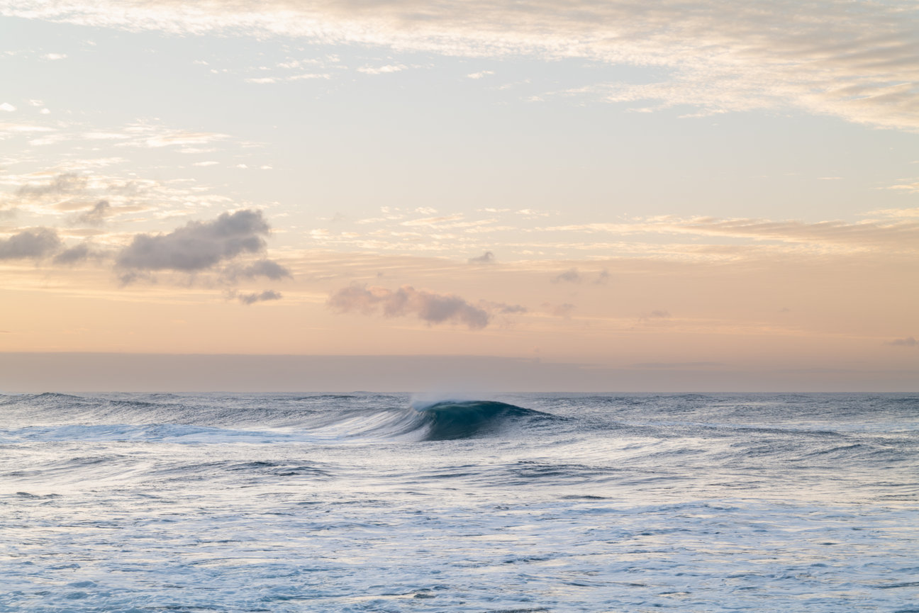 Rising Tide - minimalist seascape photograph by Andrea Bruns featuring a single turquoise wave beneath a warm Pacific sunset sky.