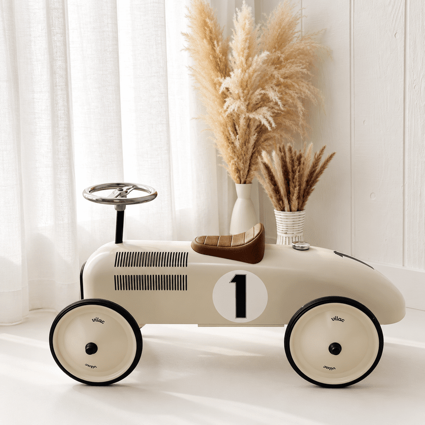 Cream vintage ride-on car with a brown seat on bright white studio flooring
