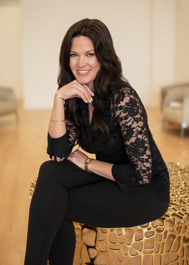 Elegant young woman in black seated on gold metal chair looking at camera, by San Diego branding photographer Stefanie Blue.