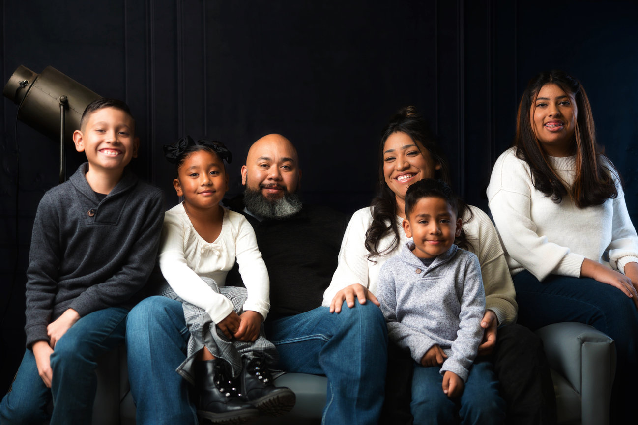 Family portrait session at West Texas Times Photography Studio in Lubbock, featuring six family members, including two adults and four children, posed together in a professional studio setting.