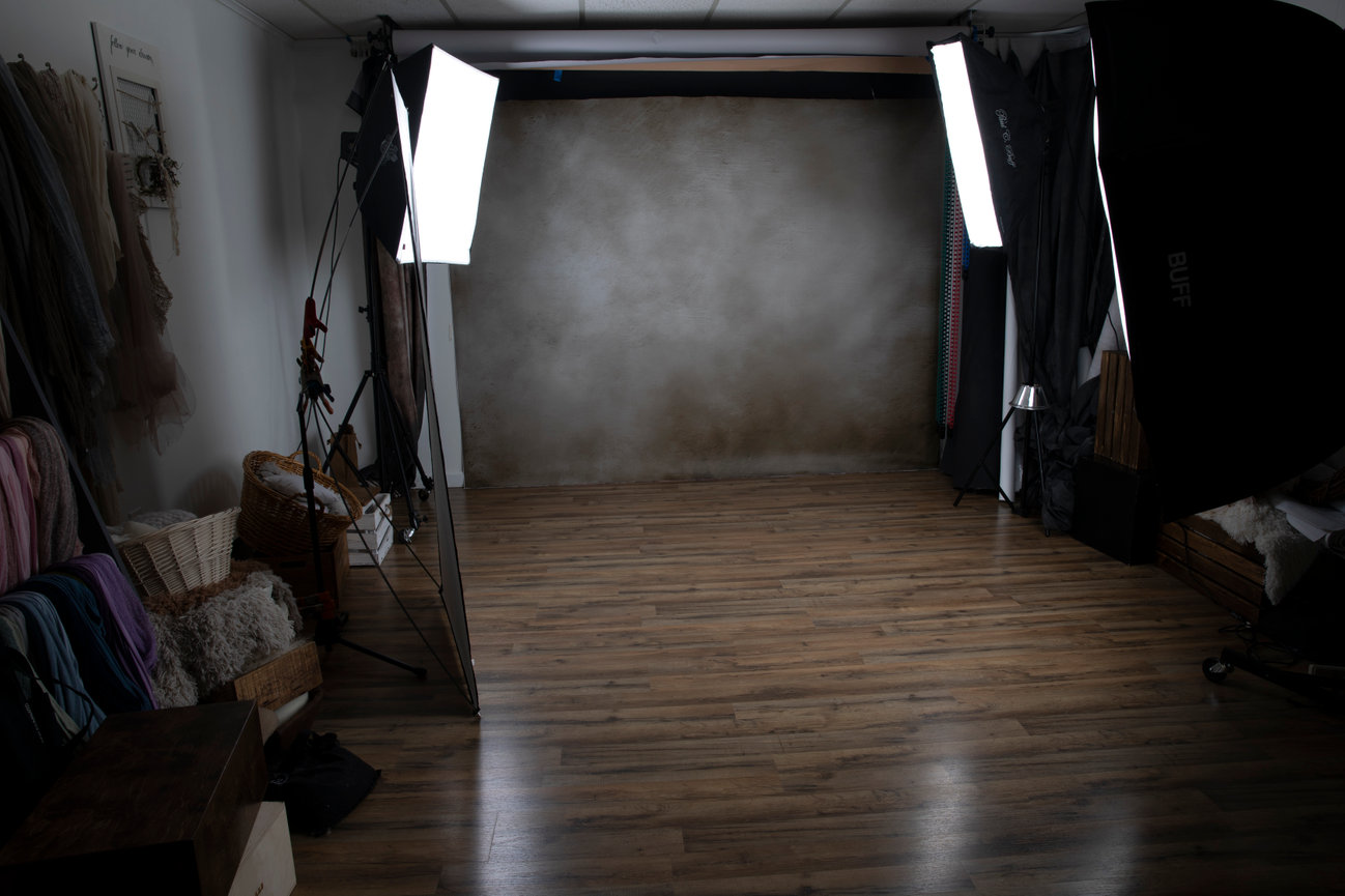 Paula Swift's Photography studio with softboxes, textured backdrop, and wooden floor. Props and fabrics are on the sides.