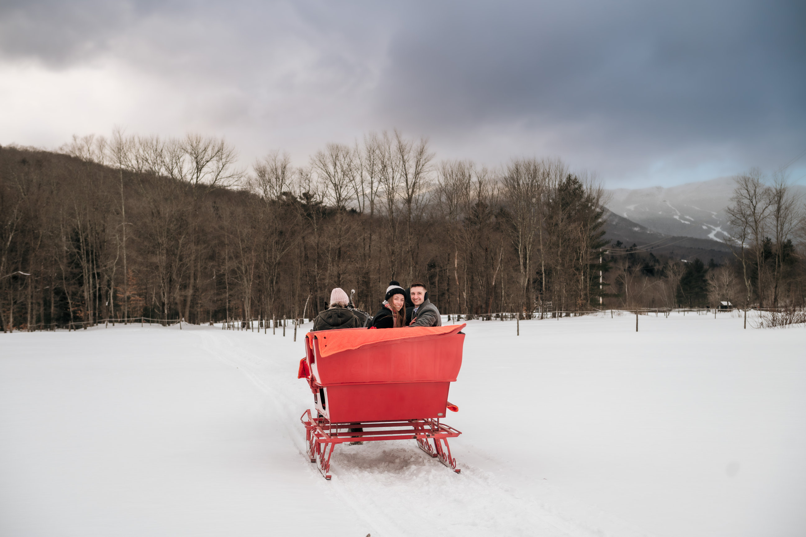 Newly engaged couple on a red sleigh ride in Stowe
