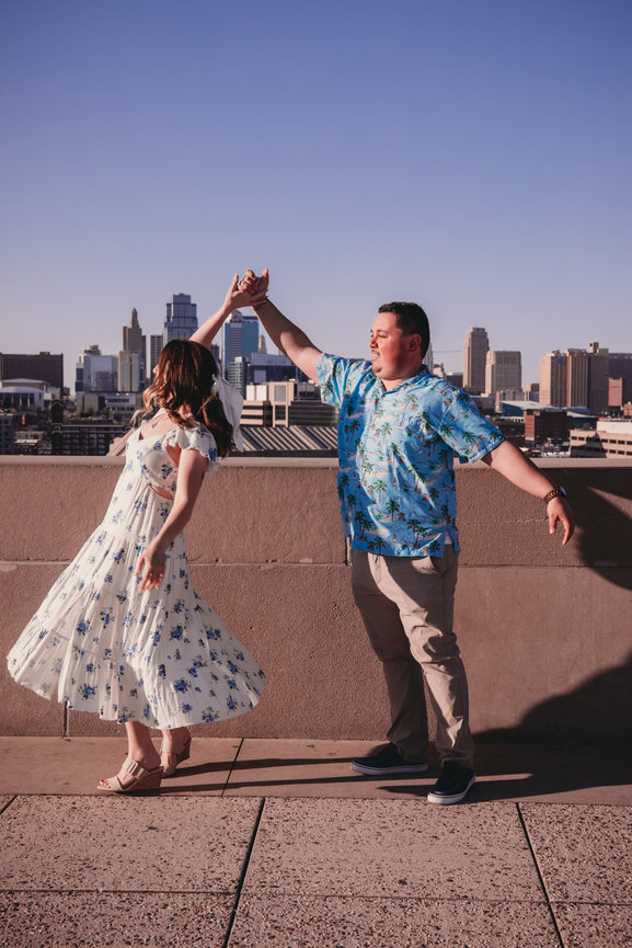 Couple dancing on a rooftop with a city skyline in the background.