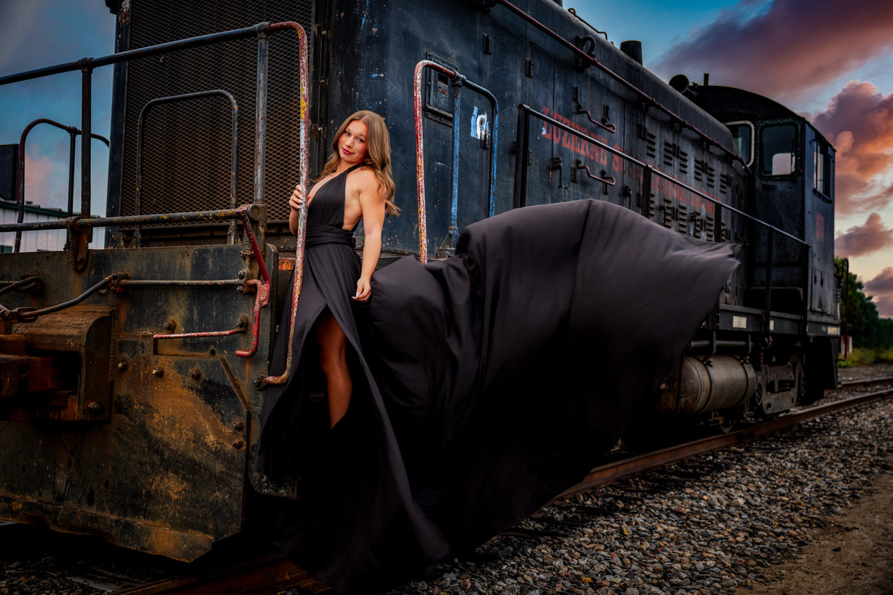 High School Senior in black gown posing on a vintage train at sunrise in Wilkes-Barre PA photographed by Darren Elias Photography.