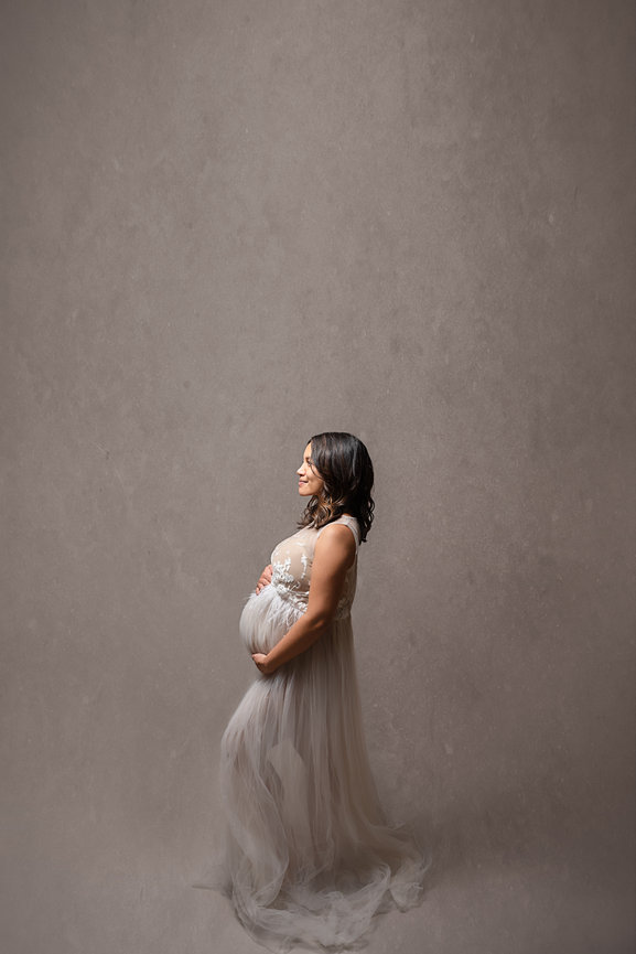 Fashion-forward maternity photo of mom in a couture gown with dramatic lighting